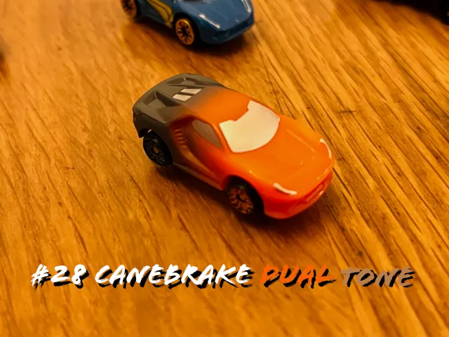 A carousel photo displaying the twenty-eighth vehicle named 'Canebrake Dual Tone' out of an array of 'Deluxe Cars', at full size. The car is painted orange with it's rear black.