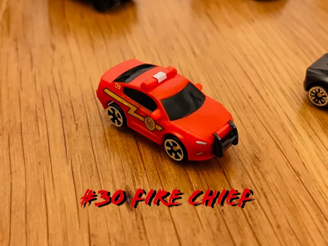 A carousel photo displaying the thirtieth vehicle named 'Fire Chief' out of an array of 'Deluxe Cars', at full size. The car is painted red with a strike of yellow lightning across the right door sides.